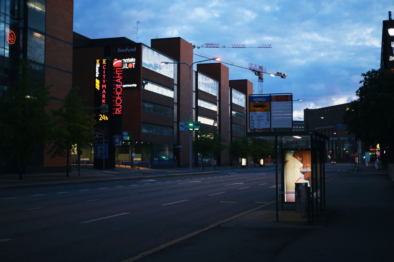 Na zdjęciu fragment ulicy w mieście, przystanek, budynki, ujęcie wieczorne